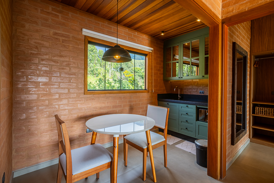 Stone fireplace with open mesh doors, a fire burning inside, two glasses of red wine and a wooden platter with cheese and crackers on the hearth.